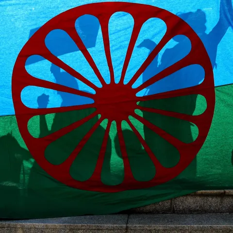 People cast shadows on the Roma flag during an anti-racism march by members of the Romanian Roma community celebrating the Romani Resistance Day in Bucharest, Romania, Saturday, May 18, 2019. On May 16, 1944 Roma prisoners in the Auschwitz concentration camp resisted an attempt by the Nazi troops to liquidate their camp, which postponed the action until August the same year. (AP Photo/Vadim Ghirda)